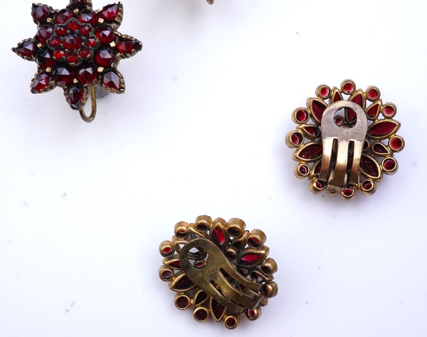 A suite of garnet and paste jewellery, comprising: a brooch, 5cm diameter; a bangle, inner circumference 16cm; two rings, sizes I and M; a pair of earrings, and a single earring, each set with rose-cut garnets; and a pai